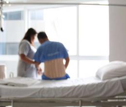 Image (blurred) of patient sitting on hospital bed with nurse standing.