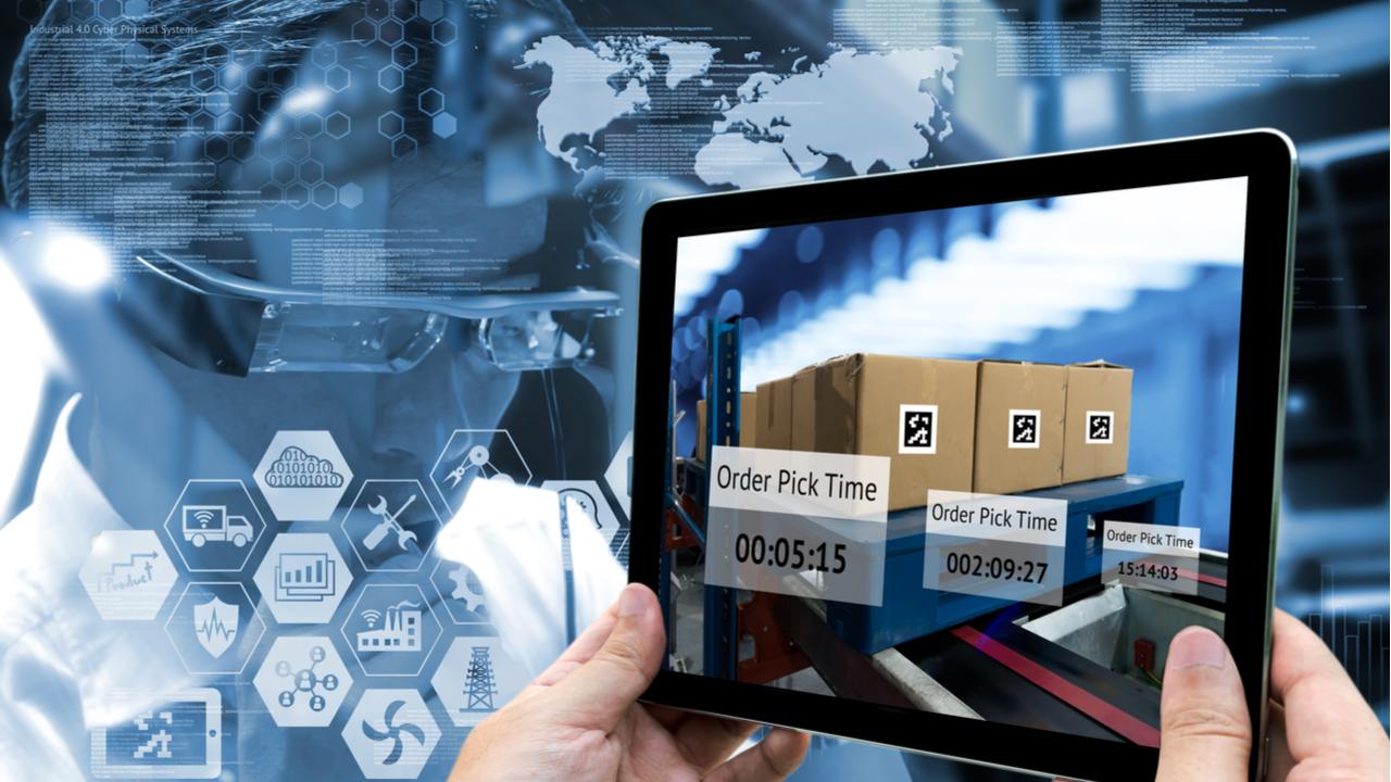 Hand holding tablet with AR application for check pick up time in smart factory warehouse.