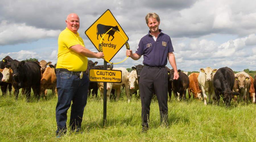 Richard Hobson, wearing yellow shirt, pictured in front of a herd of cows along with farmer client and promotional signage.